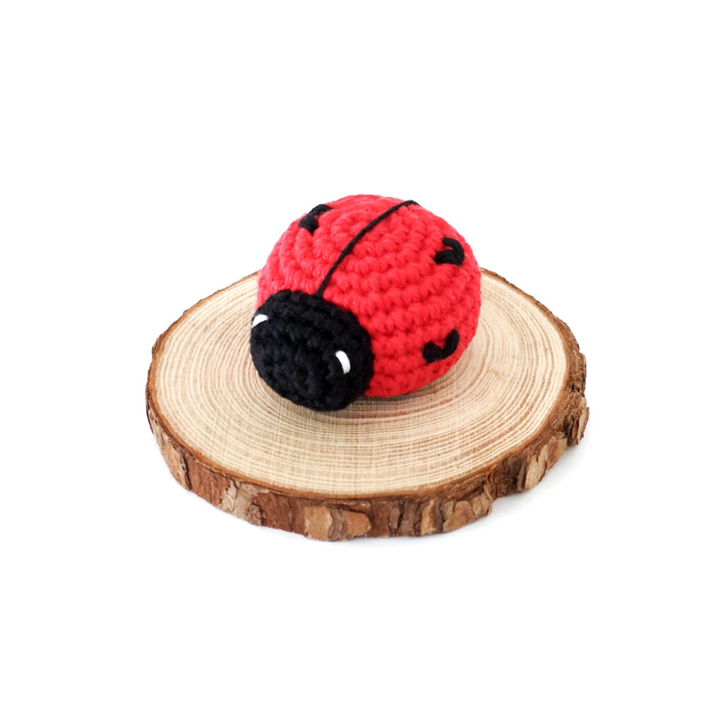Crochet love bug on a wood round.