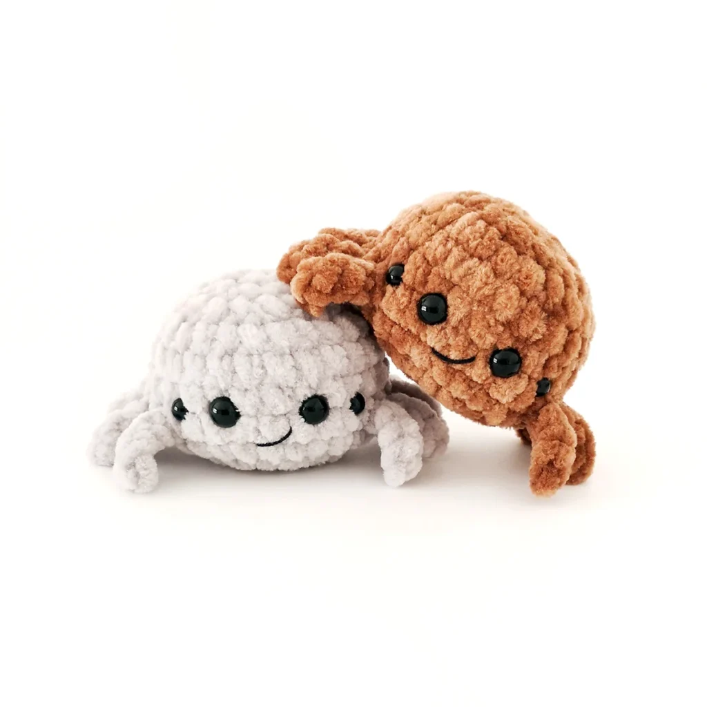 Two small crochet spider plush toys leaning against each other.