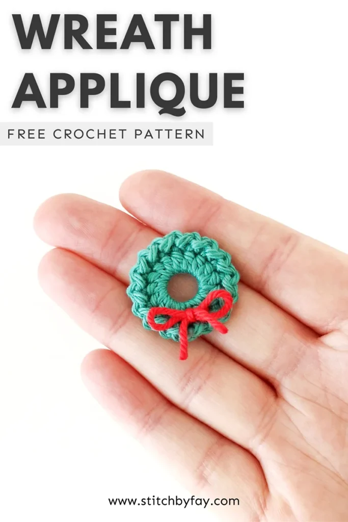 Pinterest image showing a green crochet Christmas wreath lying on the fingers of a hand against  a white background. Text overlay reads: "Wreath applique, free crochet pattern, www.stitchbyfay.com".