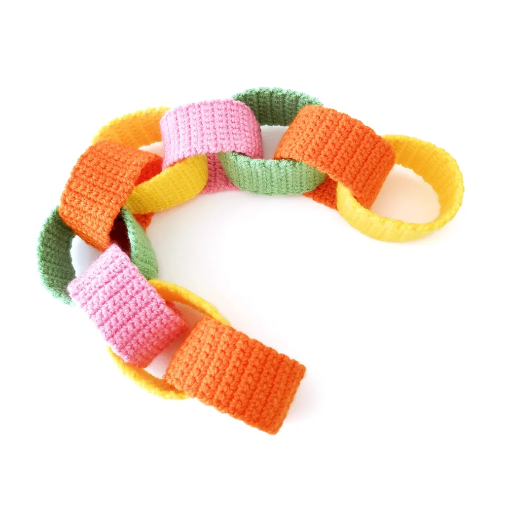 Short crochet paper chain garland with orange, yellow, pink and green chain links.