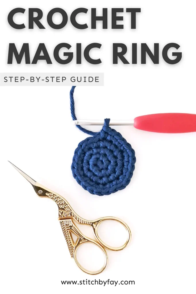 Pinterest image showing a dark blue crocheted circle started with a magic ring on a pink crochet hook with a pair of small gold scissors below. Text overlay reads: "Crochet magic ring, step-by-step guide, www.stitchbyfay.com".