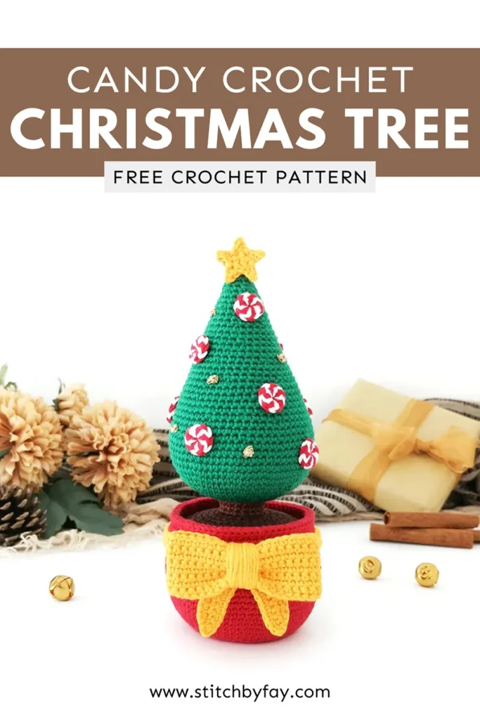 Pinterest image showing a crochet Christmas tree featuring a red pot, large yellow crochet bow and star, decorated with red and white crocheted peppermints and gold French knots with gold bells, cinnamon sticks, pinecones, fake flowers and a black and beige striped scarf in the background. Text overlay reads: "Candy crochet Christmas tree, free crochet pattern, www.stitchbyfay.com".
