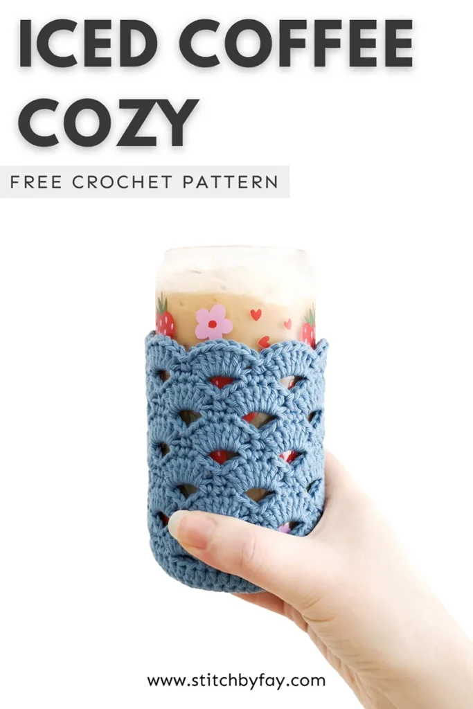 Pinterest image showing an iced coffee in a glass beer can with a strawberry design wearing a crochet coffee cozy that uses the arcade stitch, being held up against a white background. Text overlay reads: "Iced coffee cozy, free crochet pattern, www.stitchbyfay.com".