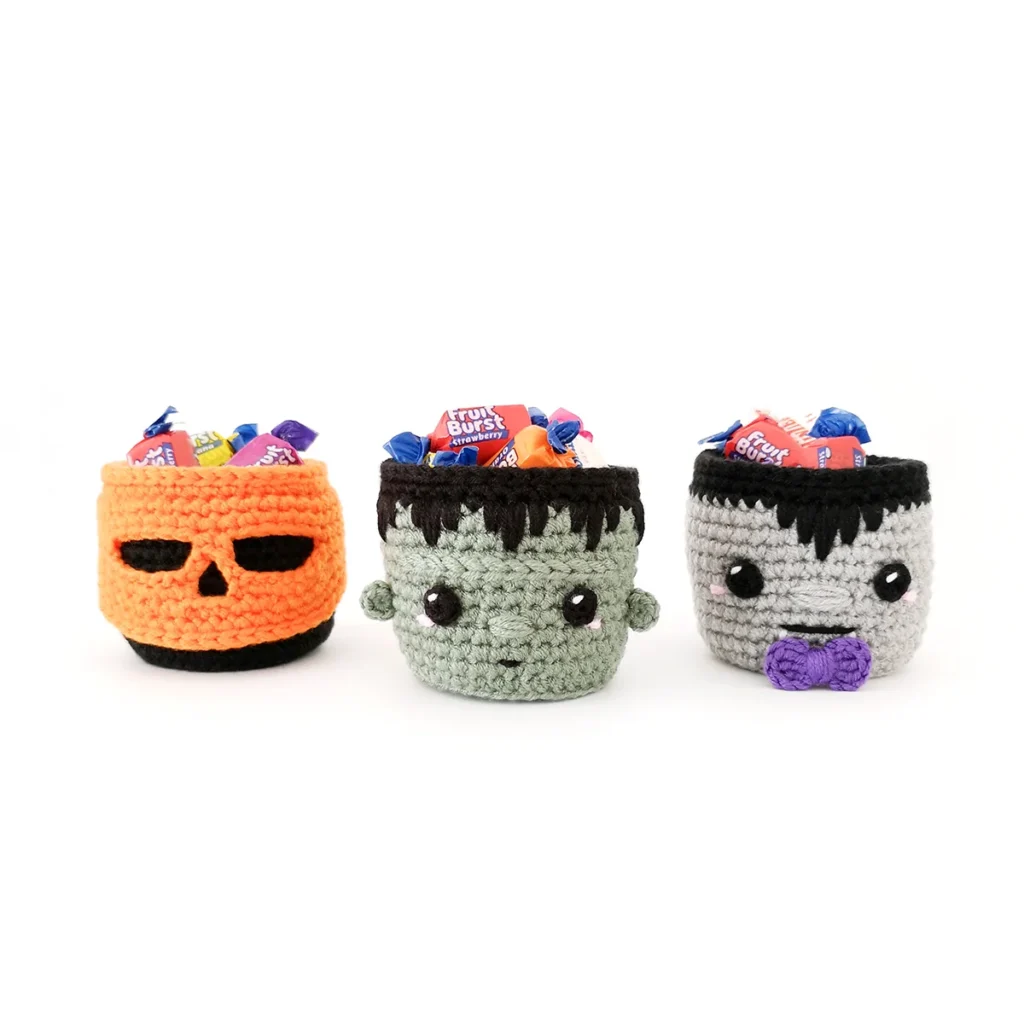 Crochet Halloween basket trio, Frankenstein, vampire and pumpkin skull, filled with wrapped candy.