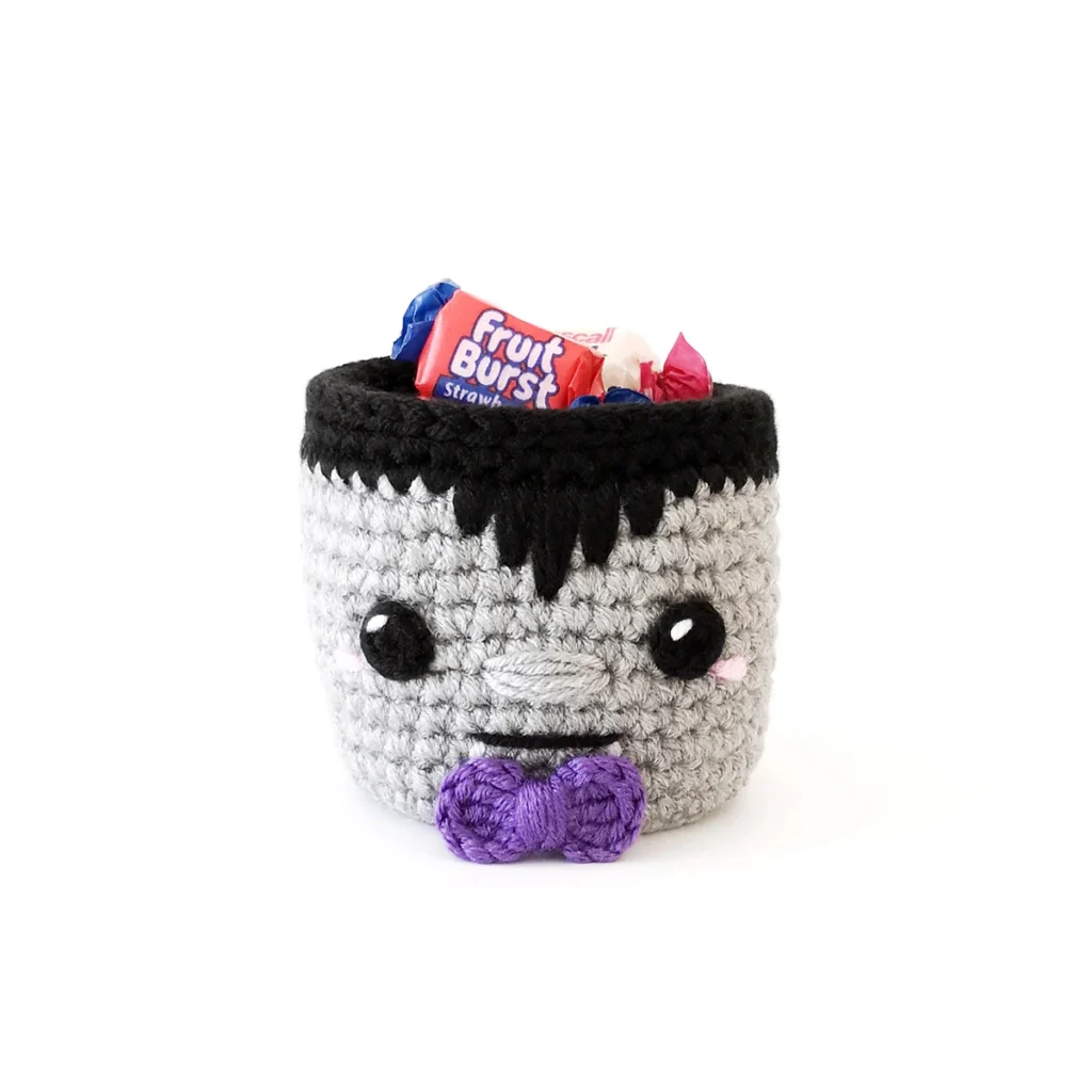 A small vampire basket with purple bow tie filled with wrapped candy.